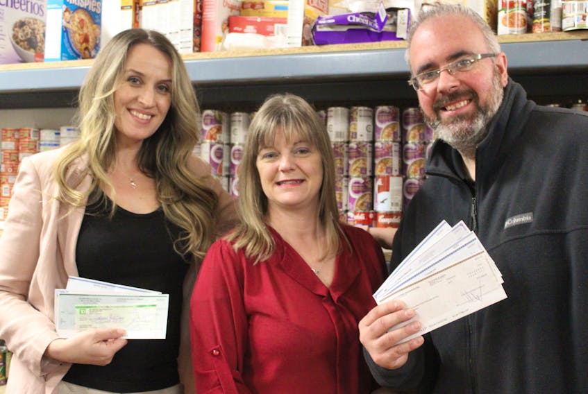 Sara Taylor of the Nook and Cranny (left) and Claudio Rambelli (Taco Bros) presents Shelly DeViller with cheques from the restaurants that participated in Burger Fest.