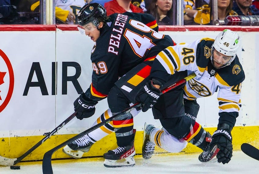 Feb 28, 2023; Calgary, Alberta, CAN; Calgary Flames left wing Jakob Pelletier (49) and Boston Bruins center David Krejci (46) battle for the puck during the third period at Scotiabank Saddledome. Mandatory Credit: Sergei Belski-USA TODAY Sports