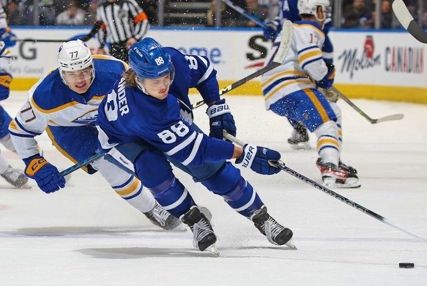 William Nylander of the Toronto Maple Leafs grabs a puck against JJ Peterka of the Buffalo Sabres  at Scotiabank Arena on March 13, 2023 in Toronto, Ontario, Canada.
