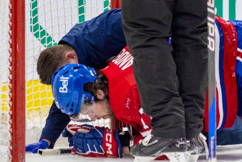 Montreal Canadiens' Josh Anderson is attended to by head athletic therapist Graham Rynbend after being taken down by Tampa Bay Lightning's Mikhail Sergachev during third period of National Hockey League game in Montreal Tuesday March 21, 2023.