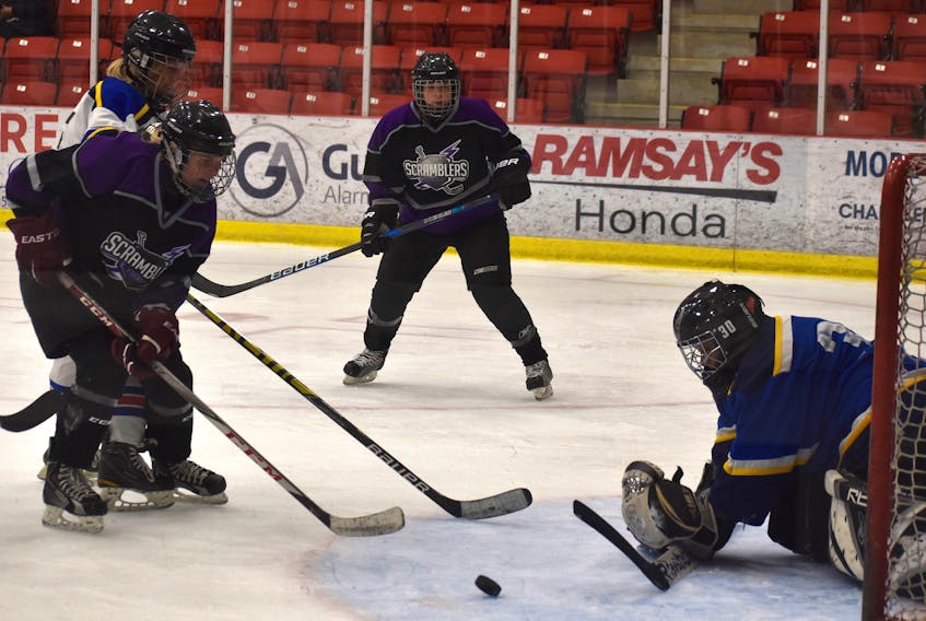 Jennifer MacInnis of the Scramblers, left, looks for the loose puck as goaltender Wendy Andrea of the Northside Heri-canes attempts to freeze it during Day 1 of the Vince Ryan Memorial Hockey Tournament at the Membertou Sport and Wellness Centre on Thursday. The Heri-canes won the game 5-3. The tournament continues until Sunday in the Cape Breton Regional Municipality. JEREMY FRASER/CAPE BRETON POST.