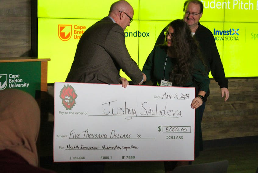 Jushya P. Sachdeva, centre, shakes Todd Graham's hand as she accepts the $5,000 cheque for winning the first Health Innovation Student Pitch competition at CBU on Saturday. On the right is Bob Pelley from Inspire Nova Scotia who announced Sachdeva was the winner out of four finalists. CAPE BRETON POST / NICOLE SULLIVAN