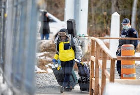 FILE PHOTO: An asylum seeker crosses the border from New York into Canada followed by a Royal Canadian Mounted Police (RCMP) officer at Roxham Road in Hemmingford, Quebec, Canada March 18, 2020.  REUTERS/Christinne Muschi/File Photo  An asylum seeker crosses the border from New York into Quebec at Roxham Road in Hemmingford, Que., in March 2020. - Christinne Muschi / Reuters file