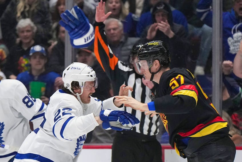 Maple Leafs' Jake McCabe (22) throws off his gloves as he fights Vancouver Canucks' Tyler Myers  during the first period of an NHL hockey game in Vancouver, on Saturday, March 4, 2023. 