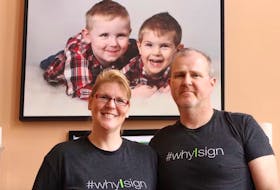 Kim and Todd Churchill pose with a photo of their two sons, Carter (right) and Hunter, in this 2019 file photo.