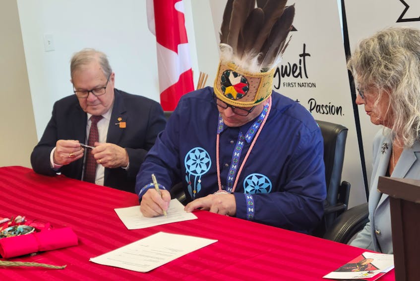 Lawrence MacAulay, left, minister of Veterans Affairs Canada, watches as Junior Gould, Chief of Abegweit First Nation, signs an agreement between Abegweit and the Department of Fisheries and Oceans that recognizes and funds a moderate livelihood fishery. Joyce Murray, right, minister of fisheries and oceans, was also on hand for the signing. Logan MacLean • The Guardian.