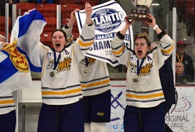 Julia MacDonald of the Northern Subway Selects, right, lifts the championship trophy over her head as teammate Sarah Fraser, left, celebrates after the team defeated the Western Flames of New Brunswick 5-0 in the final game of the Atlantic Under-18 'AAA' Female Hockey Championship at the Membertou Sport and Wellness Centre on Sunday. JEREMY FRASER/CAPE BRETON POST.