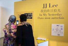 At JJ Lee’s In My Yesterday exhibition at the Canadian Museum of Immigration at Pier 21 in Halifax, the artist, right and her sister, Bonny Lee, call their father who's in Toronto. The exhibit that shows their Chinese immigrant grandfather’s documents opened May 13 and runs until July 23. Xixi Jiang/ New Canadian Media