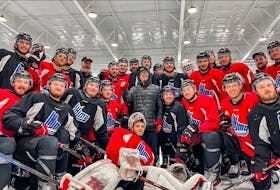 Halifax Mooseheads fan Tyler Long is surrounded by Quebec Remparts players and coaches at a practice in Dartmouth on Monday. - QMJHL
