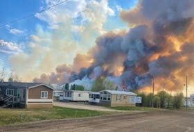 A fire can be seen behind some homes in Rainbow Lake, Alberta. Contributed.