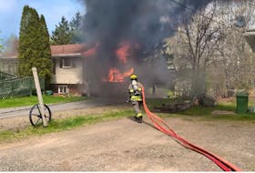 A Kentville firefighter advances a hose towards a burning house on Giffin Court in North Kentville Monday morning, May 15, 2023. One man was injured in the fire and hospitalized for treatment.