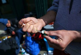 An intravenous drug user fills a syringe with street drugs in Vancouver's Downtown Eastside in 2020.