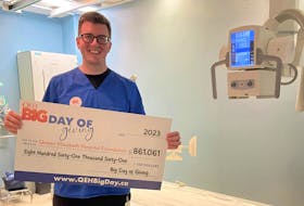 Queen Elizabeth Hospital medical radiation technologist Nicholas Lynch holds the QEH Big Day of Giving grand fundraising total of $861,061. The x-ray machine is among the equipment pieces that will be replaced with the donations. Contributed