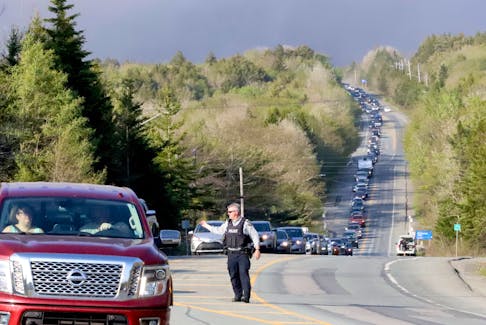 An RCMP officer directs a long line of traffic on Hammonds Plains Road as residents are evacuated from the Upper Tantallon area because of Sunday's wildfire.