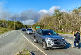 A police officer directs traffic as residents flee Sunday's wildfire in the Upper Tantallon area.