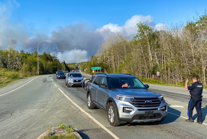 A police officer directs traffic as residents flee Sunday's wildfire in the Upper Tantallon area.