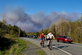 A pair of young cycists are seen as residents evacuate subdivisions during a wildfire  in the Upper Tantallon area,  on Hammonds Plains Road in Upper Tantallon Sunday May 28, 2023.


TIM KROCHAK PHOTO