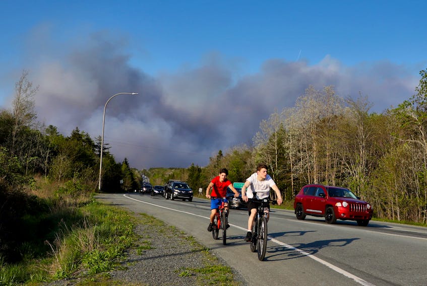 A pair of young cycists are seen as residents evacuate subdivisions during a wildfire  in the Upper Tantallon area,  on Hammonds Plains Road in Upper Tantallon Sunday May 28, 2023.


TIM KROCHAK PHOTO