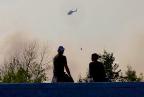 A couple watch and natural resources helicopter prepare to drop water on a fire behind farmers dairy on Hammonds Plains Road near Bedford, May 30, 2023
TIM KROCHAK PHOTO