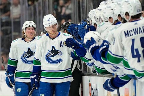 Vancouver Canucks center Elias Pettersson, second from left, celebrates his 100th point with teammates on the bench as he is followed by right wing Brock Boeser during the first period against the Anaheim Ducks on Tuesday, April 11, 2023, in Anaheim, Calif.