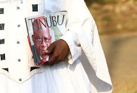 An All Progressives Congress (APC) supporter carries a book with a picture of the APC's Bola Tinubu who was declared the winner of Nigeria's 2023 presidential election. REUTERS
