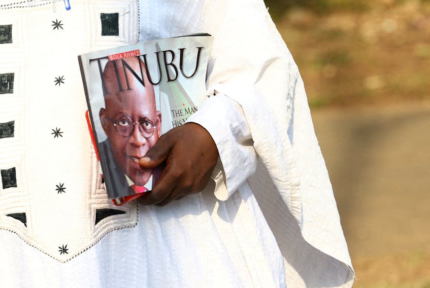 An All Progressives Congress (APC) supporter carries a book with a picture of the APC's Bola Tinubu who was declared the winner of Nigeria's 2023 presidential election. REUTERS