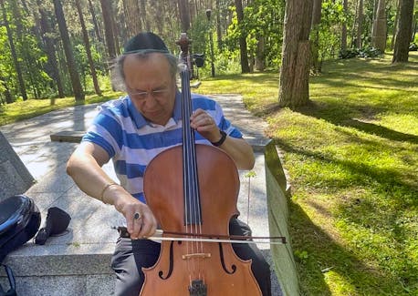 Shimon Walt plays a borrowed cello at Ponar, where his family was killed. - Courtesy of Peggy and Shimon Walt