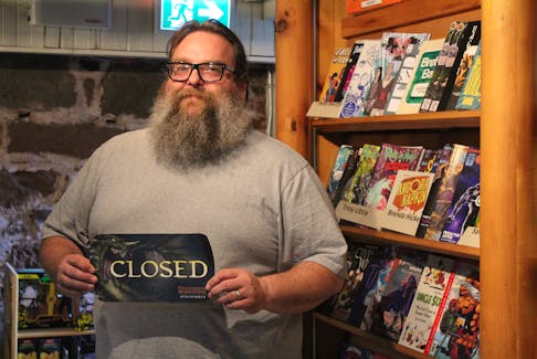 Dylan Miller, owner of Lightning Bolt Comics in Charlottetown, holds up a closed sign in his shop on June 14. Miller has decided to close his comic book store after 24 years in business. Rafe Wright • The Guardian