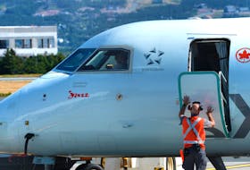 A member of the ground crew at St. John’s International Airport closes the door to an Air Canada Jazz Dash-8 aircraft as it prepares for takeoff. -Keith Gosse/The Telegram file photo