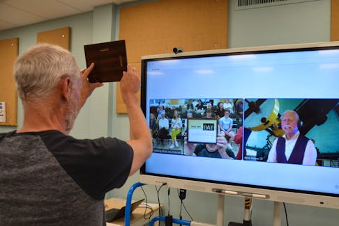 Jeff Hafting, chairperson of the Annapolis Innovation Lab Society, holds up the plaque from David Balam so the astronomer, appearing online from the Dominion Astrophysical Observatory in Victoria, B.C., can see it.