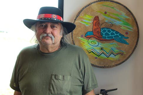 Mi'kmaq artist Alan Syliboy standing beside one of his drum paintings in his new studio. Brendyn Creamer
