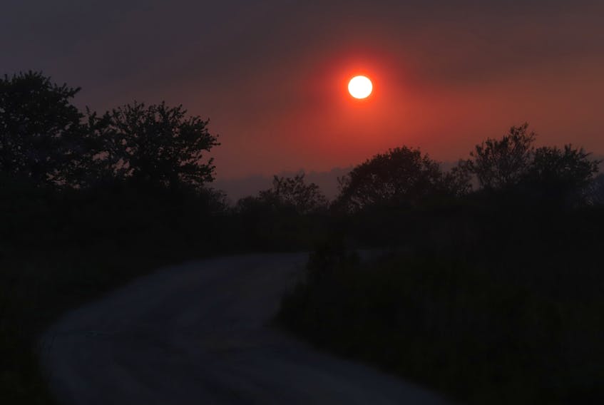 The smoke from the Barrington wildfire, works as a filter to the setting sun, seen at a winding road near Lockport, NS Thursday evening June 1, 2023.

TIM KROCHAK PHOTO