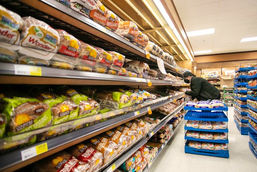  A worker restocks shelves in the bakery and bread aisle at a grocery store in Halifax. Canada Bread has settled allegations it took part in a price-fixing scheme that regulators contend began in 2001 and spanned at least 14 years.