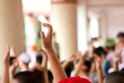 Students with hands raised in a classroom.