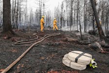 Annapolis Royal firefighters Jason Rock, left, and Anthony Lopiandowski spray hot spots in the Birchtown area in Shelburne County, on Saturday morning, June 3, as part of the wildfire response. COMMUNICATIONS NOVA SCOTIA
