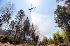 A helicopter contracted by the Province drops water on a hot spot behind Yankeetown Road as an excavator makes a fire break on Thursday. - CNS