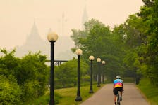 A cyclist rides as smoke from wildfires in Ontario and Quebec obscures Parliament Hill in Ottawa on Tuesday, June 6, 2023.