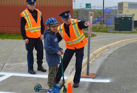 Police officers teach first-grade student Alexander Smith to look both ways before crossing the street. From left are Cadet Const. Josh Musial, Smith and Const. Gary Fraser. EMILY CONOHAN/CAPE BRETON POST
