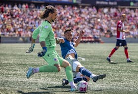 Tiago Coimbra of the HFX Wanderers slides to get the ball away from Atletico Ottawa keeper Nathan Ingham during a Canadian Premier League match in Ottawa. - Canadian Premier League
