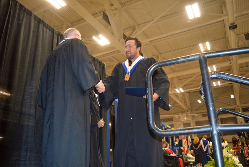 Tuma Stevens, right, is congratulated while leaving the stage during Friday's convocation ceremonies for the Nova Scotia Community College Marconi Campus. Stevens is a graduate of the business administration program. Ceremonies took place at the Membertou Sport and Wellness Centre. GREG MCNEIL/CAPE BRETON POST