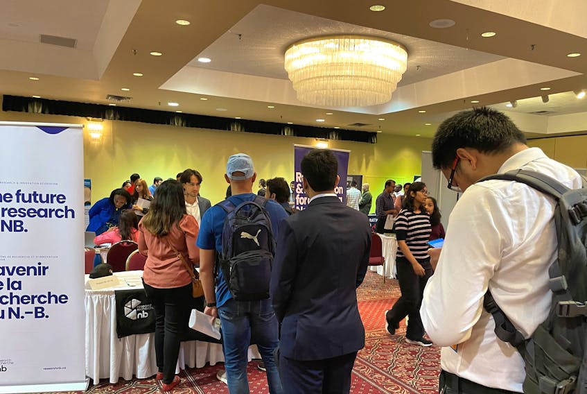 Students and newcomers line up at a booth Friday at a Fredericton job fair. The gathering was viewed as an opportunity for immigrants to get their foot in the door and to arrange potential interviews with multiple employers. (Michael Staples photo)
