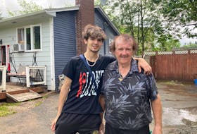 Walter Fowler and his grandson, Corbin, in front of his Bedford home, which remained flooded on Sunday.