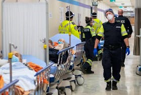 Paramedics transfer patients to the emergency room triage at Toronto's Humber River Hospital during the COVID-19 pandemic, but must leave them in the hallway due to full capacity.