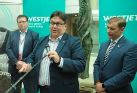 WestJet vice-president of external affairs Andrew Gibbons answers a reporter's question during a scrum with media at St. John's International Airport Monday. Stand beside him, from the left, are St. John's International Airport Authority CEO Dennis Hogan and Newfoundland and Labrador Premier Andrew Furey.  — Andrew Robinson/The Telegram