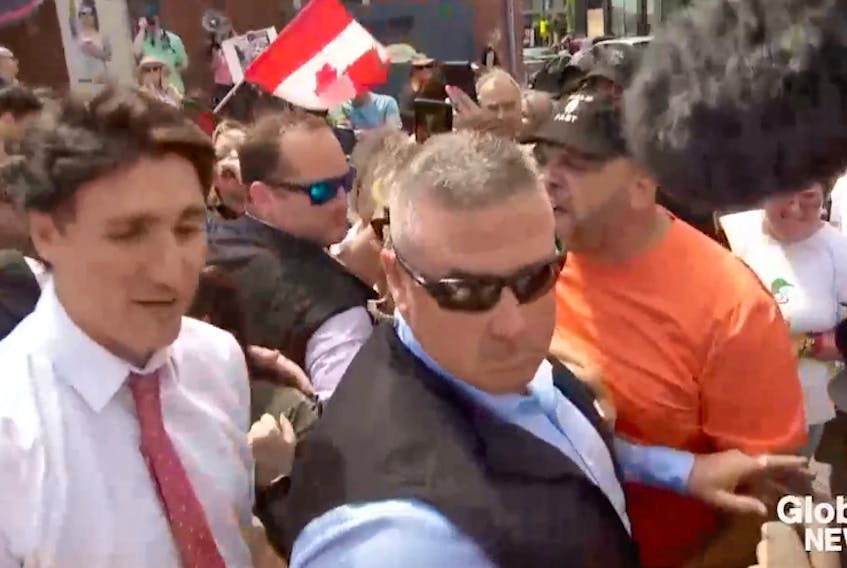 In this screenshot from a Global News video, a protester curses Prime Minister Justin Trudeau as he is surrounded by his security detail during a visit to Belleville, Ont., July 21, 2023. - Screenshot