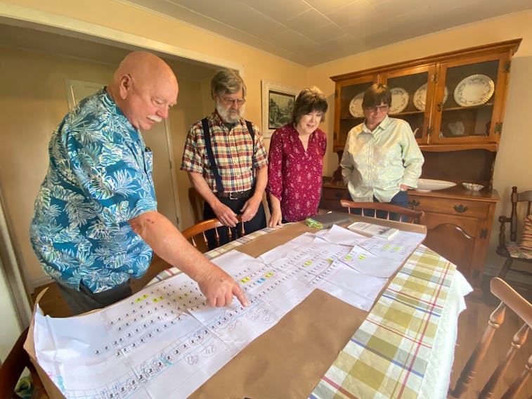 George Snell, left, EJ Gaudet, Jeanne Snell and Patricia Gaudet look at a Gaudet family tree. The poster traces siblings EJ and Jeanne's direct ancestors. – Kristin Gardiner/SaltWire