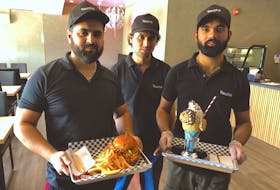From the left, Sharvan Gandhi, Muhammad Ali and Sheraz Ali, serve up a butter chicken sandwich and a large cookie monster milkshake at their new restaurant on Prince Street called Touché — Fusion Food & Gourmet Shakes. GREG MCNEIL/CAPE BRETON POST