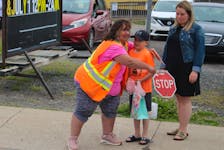 Crossing guard Georgina Lovell, right, leans in to give Blake Scott, 7, a hug as he tells her he is excited for summer vacation while his mother Miranda MacDonald waits at the crosswalk near Jubilee Elementary School in Sydney Mines. NICOLE SULLIVAN/CAPE BRETON POST