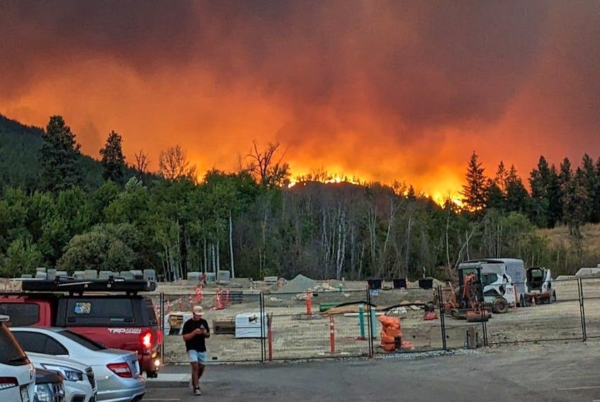 The McDougall Creek wildfire burns on the mountainside above houses in West Kelowna, B.C., on Thursday, August 17, 2023. Photo was taken by Chris Schneider as he evacuated his West Kelowna apartment. 