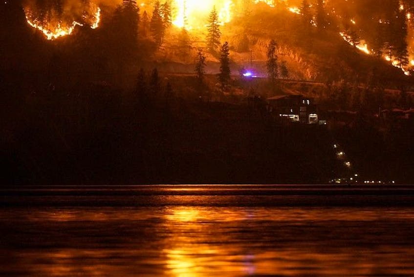  The McDougall Creek wildfire burns on the mountainside above lakefront homes, in West Kelowna, B.C., on Friday, August 18, 2023.